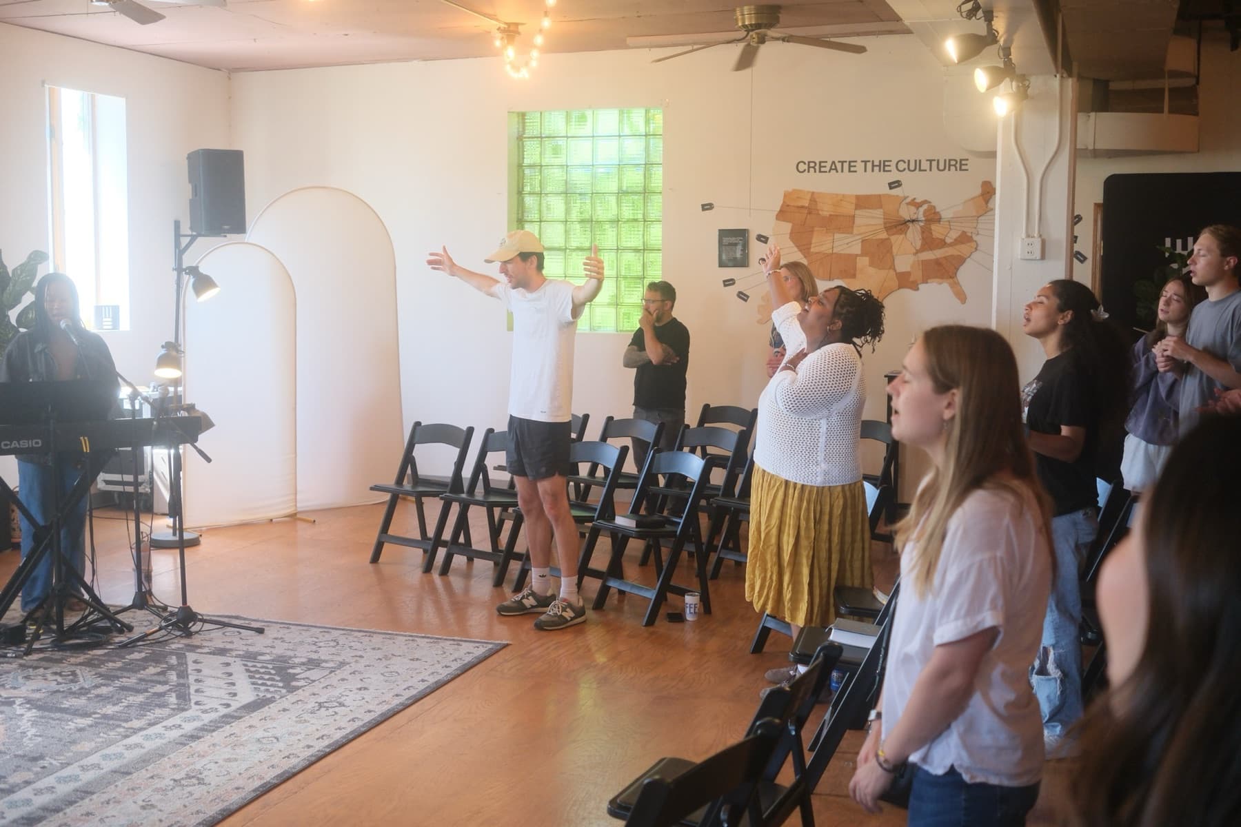 A New Culture Church member worshiping with hands raised beneath a Create the Culture map of the United States