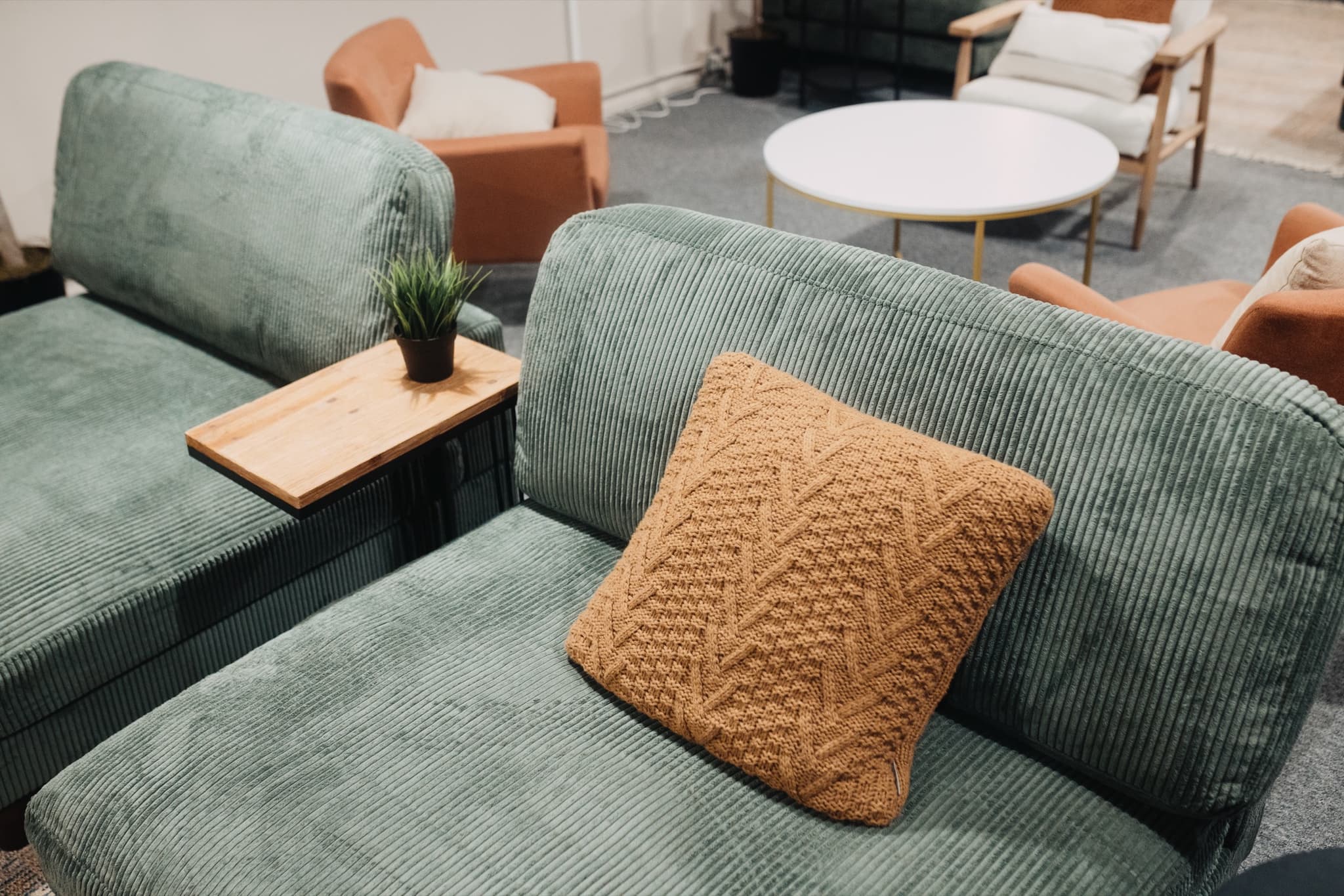 A knit pillow on a green corduroy sofa in The Living Room in downtown Madison