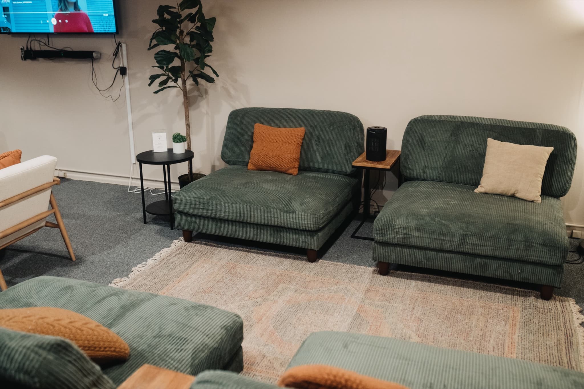 Green corduroy chaises and a soft rug in The Living Room, a rentable space in downtown Madison