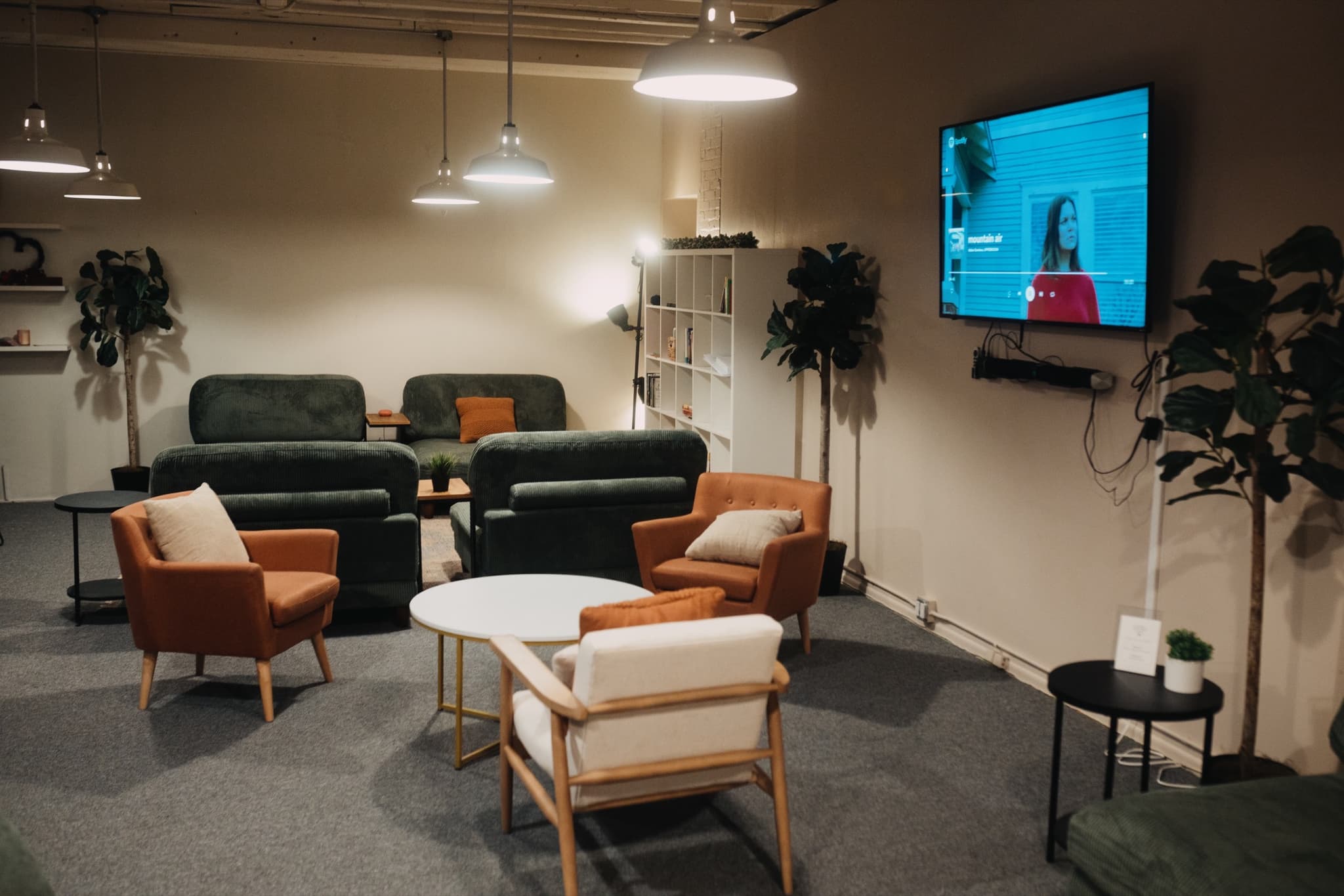 The Living Room lounge in downtown Madison, with green corduroy sofas, rust armchairs, and plants